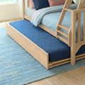 Light wood bunk bed with navy blue pull-out trundle mattress on blue area rug — space-saving kids bedroom furniture