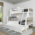 White wooden bunk bed with ladder and pull-out trundle, black-and-white bedding in a modern Scandinavian kids' bedroom with wall sconces and natural wood accents