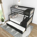 Modern black wooden twin-over-full bunk bed with staircase and pull-out trundle in bright kids' bedroom, white grid bedding, decorative pillows, striped rug and potted plant by window
