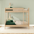 Modern wooden twin-over-twin bunk bed in kids' bedroom with emerald green velvet bedding, cream pillows, ladder, wall sconces and mint green paneled wall