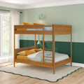 Modern wooden bunk bed with ladder in green two-tone kids' bedroom, striped bedding, mustard pillows and natural window light