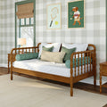 Cozy bedroom with wooden spindle daybed, green plaid wallpaper, white and sage decorative pillows, tennis-themed framed art and window with burlap roman shade