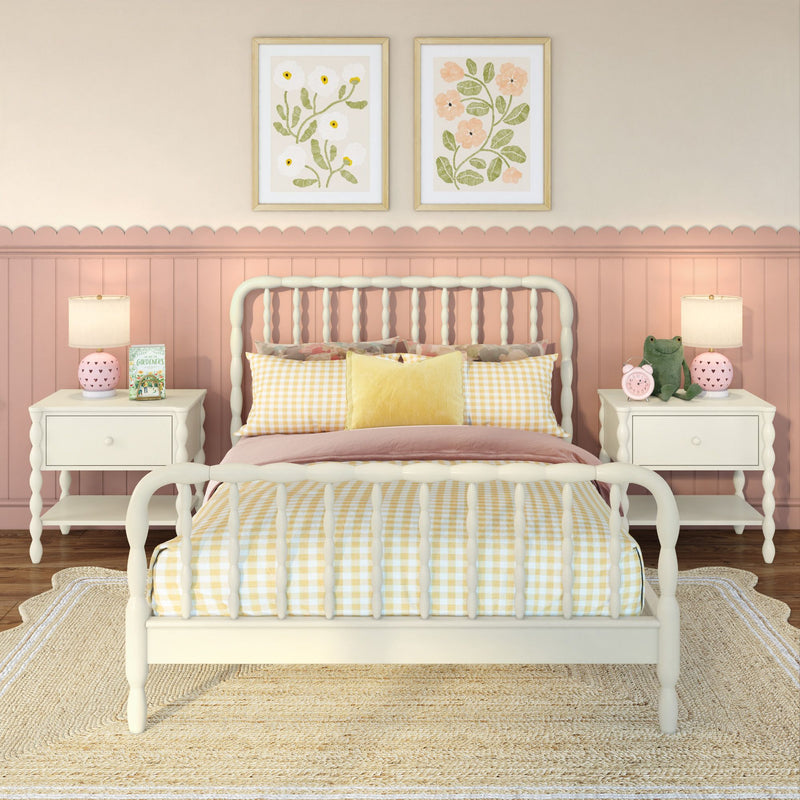 Cozy girls bedroom nursery with white spindle bed frame and yellow gingham bedding, pink scalloped wainscoting, matching white nightstands with lamps and plush frog, floral wall art and woven jute rug