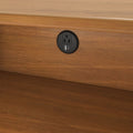 Round recessed black power outlet with standard AC socket and USB-A and USB-C charging ports installed in a wooden desk panel