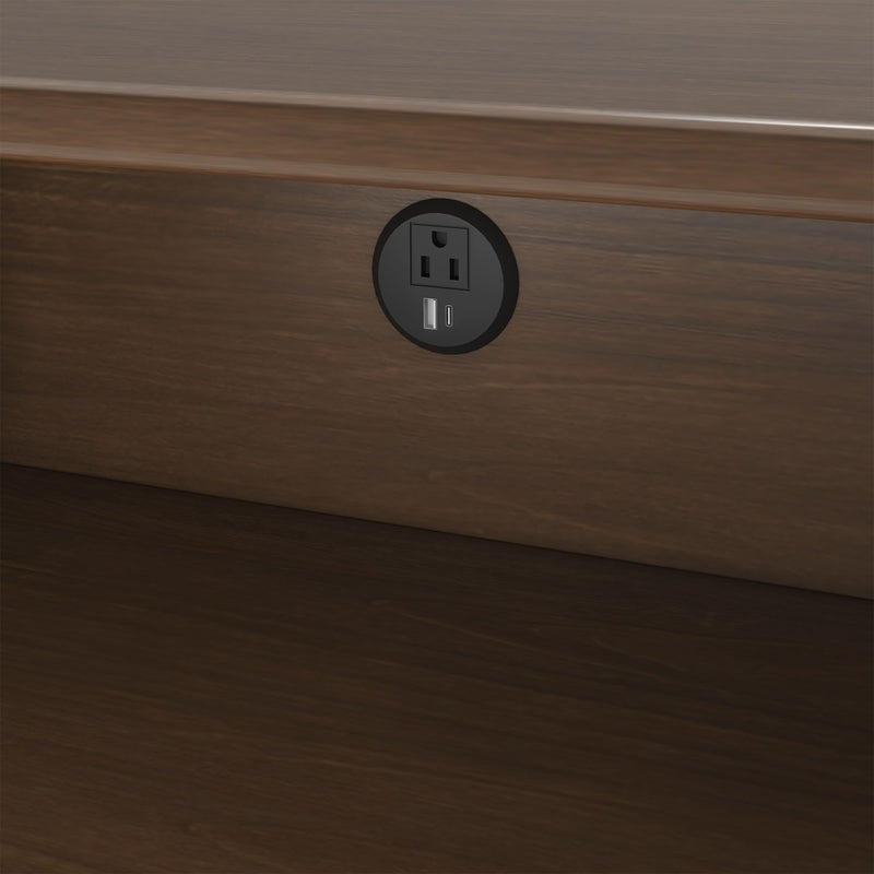 Modern round recessed wall outlet with AC socket and USB-A and USB-C charging ports installed in dark wood baseboard for bedside charging