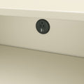 Round recessed black power outlet with AC socket and USB-A/USB-C charging ports installed in a beige wall under a desk