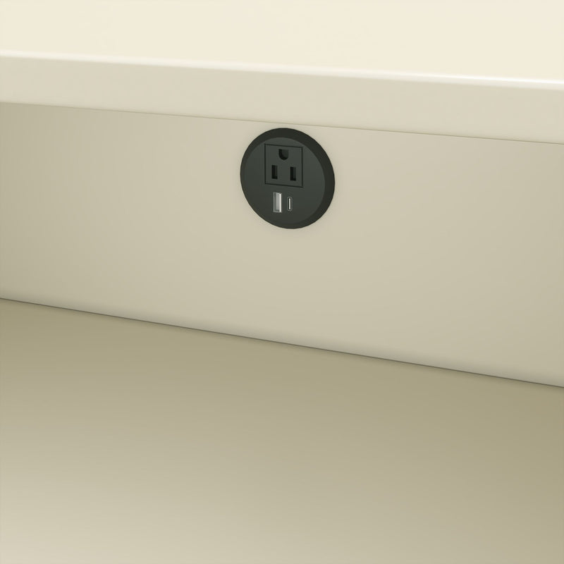 Round recessed black power outlet with AC socket and USB-A/USB-C charging ports installed in a beige wall under a desk