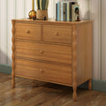 Oak wooden dresser chest of drawers on hardwood floor with brass lamp, smiling potted plant and books against striped wallpaper
