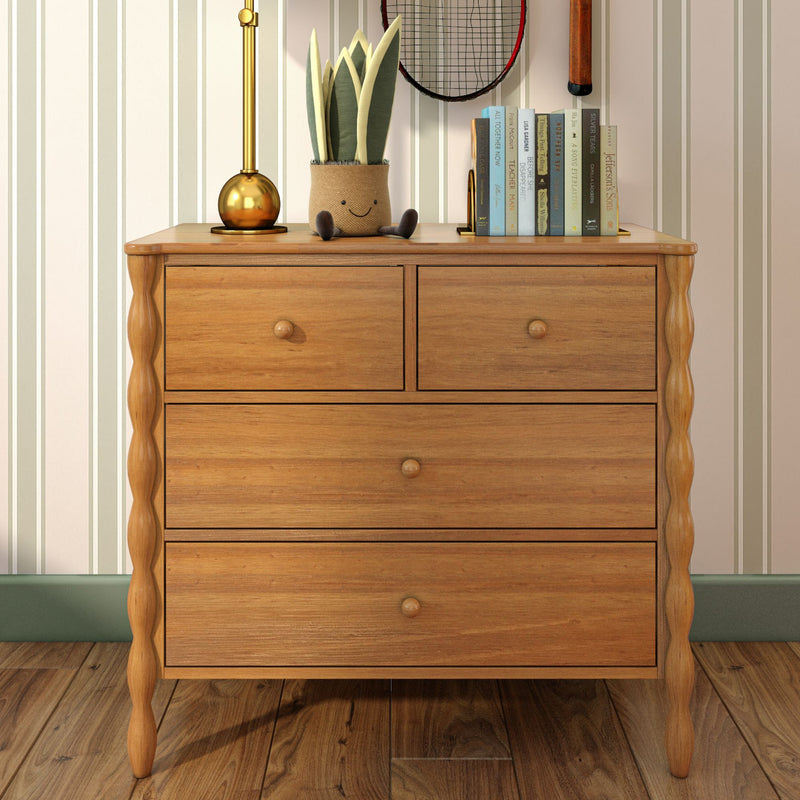 Wooden dresser with brass lamp, smiling fabric potted plant, stacked books and vintage tennis racket — rustic bedroom decor