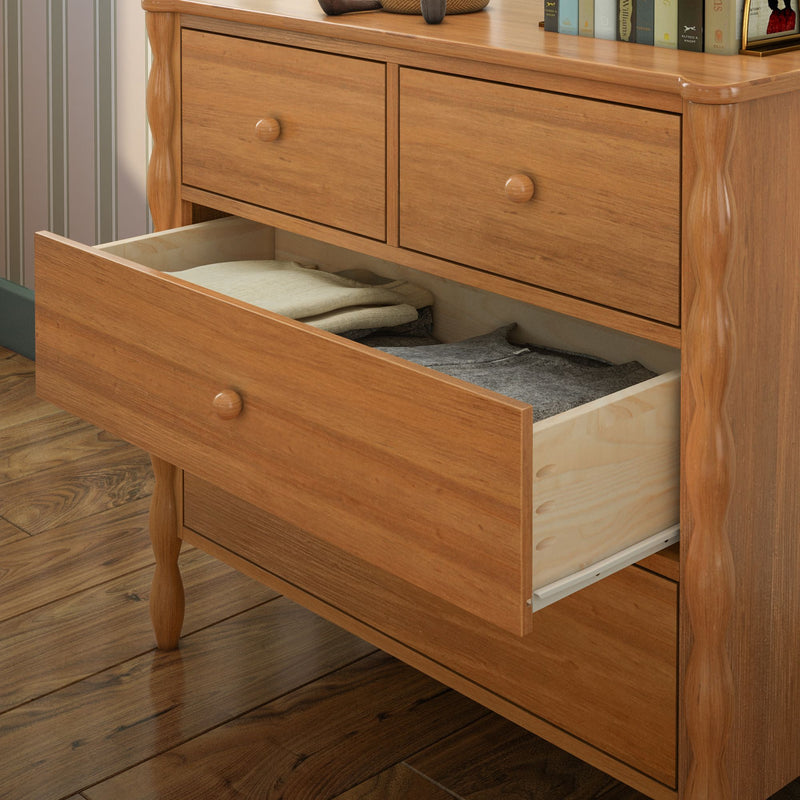 Solid wood dresser with natural oak finish and wooden knobs, open drawer with folded clothes — bedroom storage chest on hardwood floor