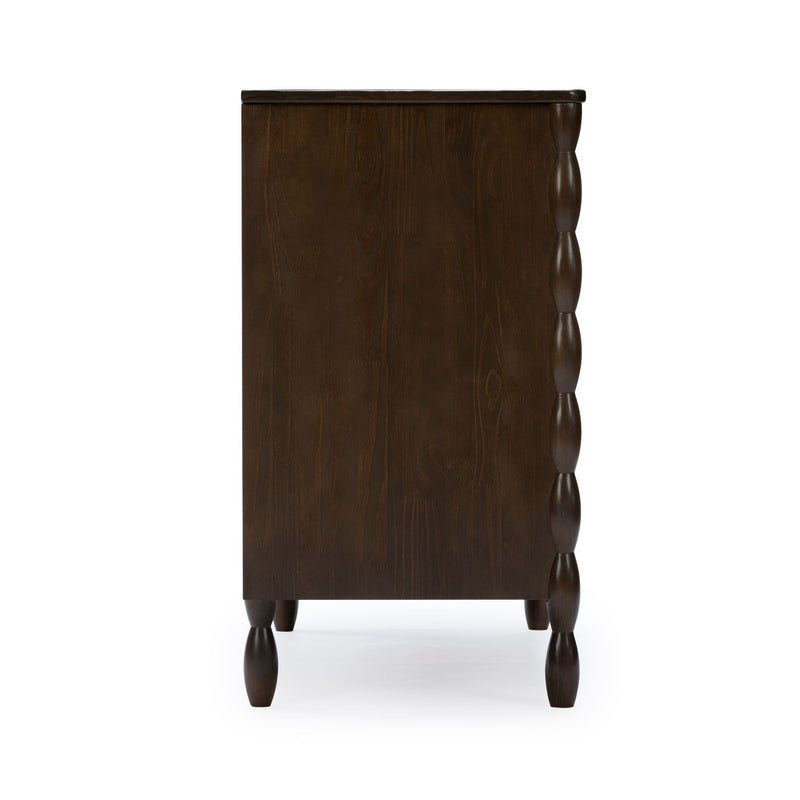 Dark brown wooden dresser side view with turned spindle legs and carved scalloped side detailing, farmhouse-style chest of drawers for bedroom