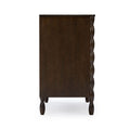 Dark brown wooden dresser side view with turned legs and scalloped side molding, classic bedroom chest of drawers