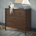 Dark wood dresser topped with a knitted octopus plush, decorative sailboat and potted plant over a blue plaid rug, coastal nursery decor