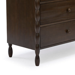 Close-up of dark brown wooden dresser corner with turned spindle legs, round drawer knobs and two drawers, espresso-finish bedroom storage chest
