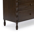 Close-up of dark brown walnut-finish wooden dresser showing spindle-style turned legs, carved vertical posts and drawer fronts with round wooden knobs