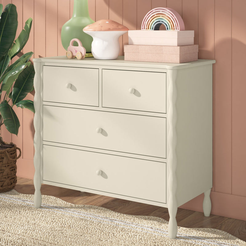 White vintage dresser in pastel nursery with wooden rainbow toy, mushroom ceramic vase, green planter, woven jute rug and pink shiplap wall