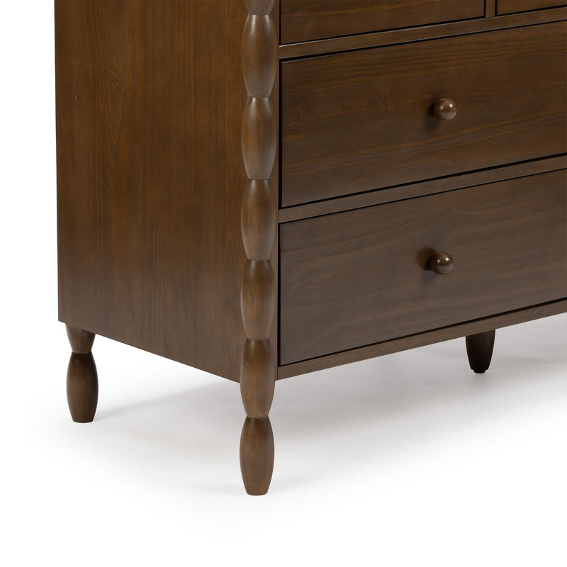 Close-up of brown wooden dresser with turned spindle corner detail, tapered turned legs and round knob drawer pulls in walnut finish