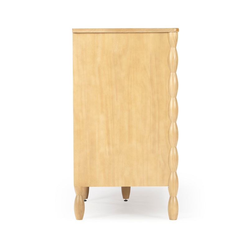 Side view of light wood chest of drawers with natural finish, turned legs and carved scalloped front edge.