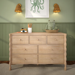 Natural wood six-drawer nursery dresser against sage green wall with plush frog in woven basket, wooden toy camera, pencil cup, octopus wall art and rattan sconces — children's room storage and decor