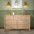 Light wood kids dresser in green paneled nursery with plush frog in woven basket, wooden toy camera, pencil cup, octopus wall art and rattan wall sconces, modern nursery decor