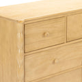 Light pine wooden dresser with round knobs and carved vertical trim, three-drawer chest for bedroom storage with natural finish