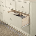 Cream wooden dresser with open drawer showing folded neutral clothing and natural wood drawer interior on woven jute rug, bedroom storage furniture