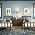 Coastal kids' twin bedroom with wooden spindle beds, navy plaid rug, sailboat decor on a dark wood nightstand, plush octopus and frog toys, framed fish and feather wall art, brass wall sconce and soft blue walls