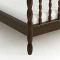 Close-up of dark wood spindle bed frame corner with white quilted mattress — traditional farmhouse bedroom furniture
