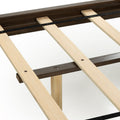 Close-up of platform bed frame wooden slats and dark wood side rails showing support system with black fabric strap