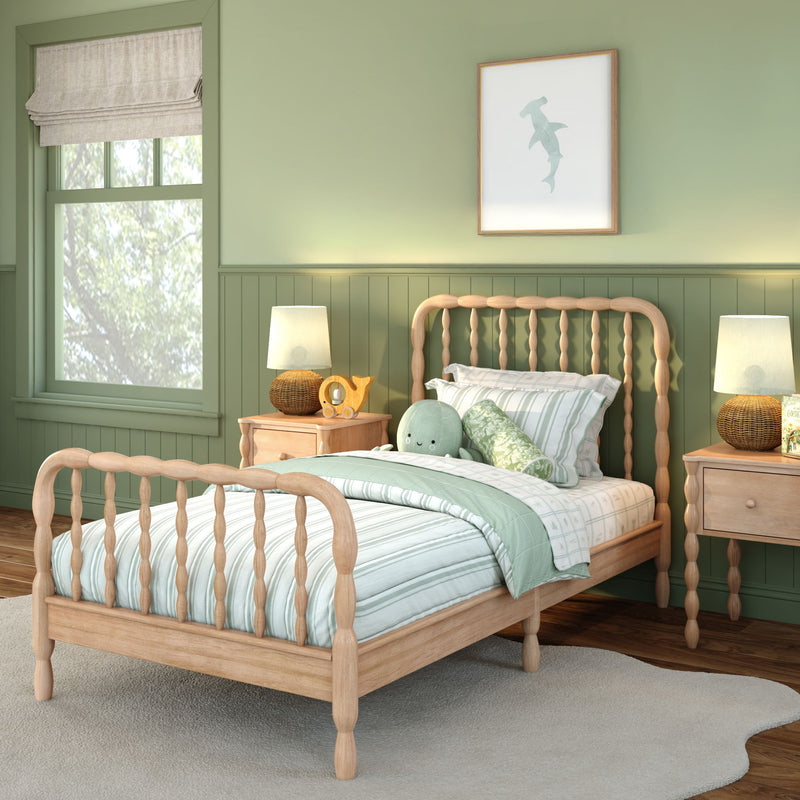 Children's bedroom with natural wood spindle twin bed, mint-green striped bedding, green paneled walls, shark wall art, bedside tables with lamps and plush toy.