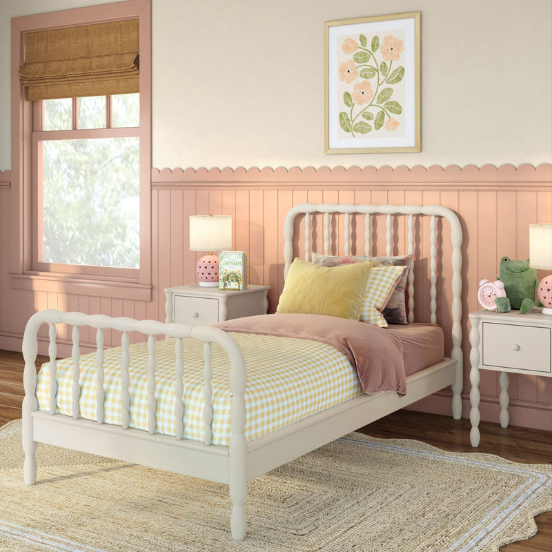 Pink nursery with white spindle bed, yellow gingham bedding, scalloped wainscoting and nightstand lamp