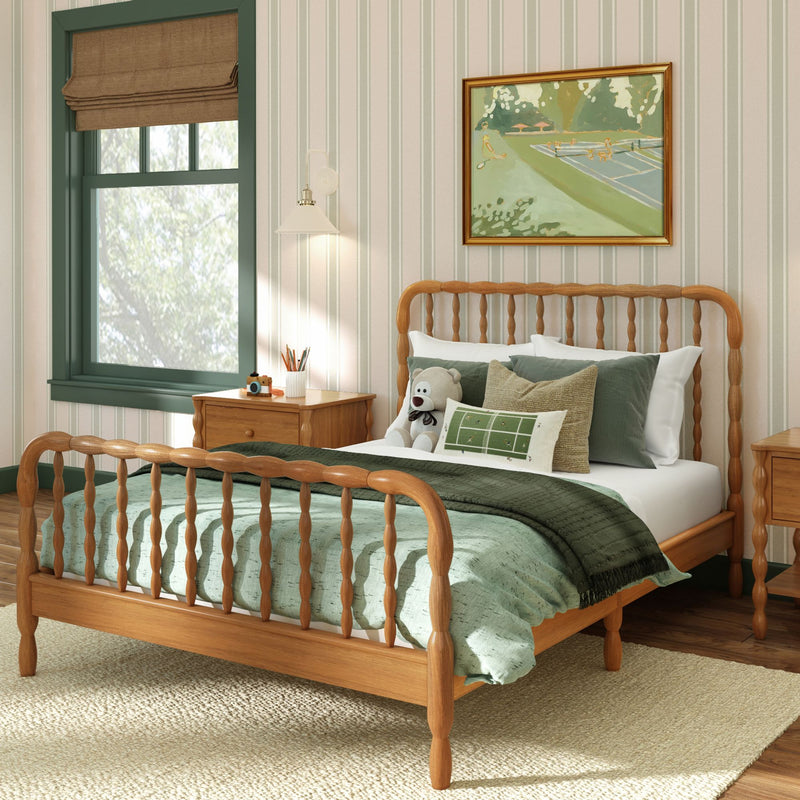 Farmhouse-style bedroom with wooden spindle bed, green linens and blanket, stuffed bear on pillows, wood nightstands and striped wallpaper