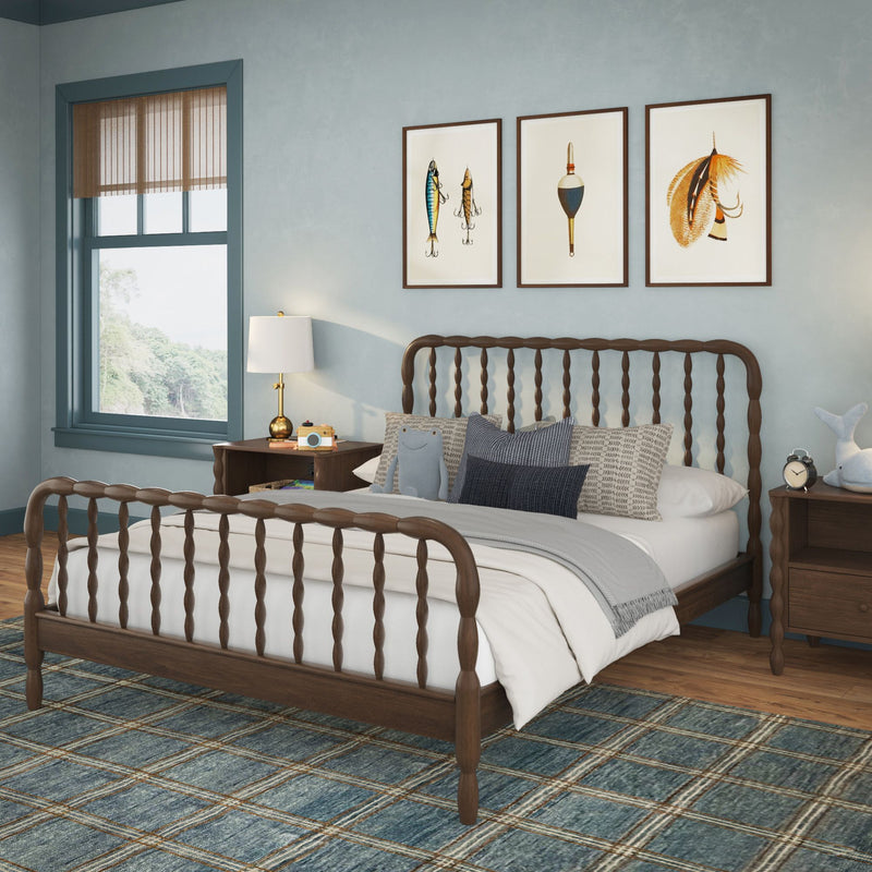 Coastal farmhouse bedroom interior with wooden spindle bed, blue plaid area rug, gray bedding, wooden nightstands, brass lamp and nautical framed art