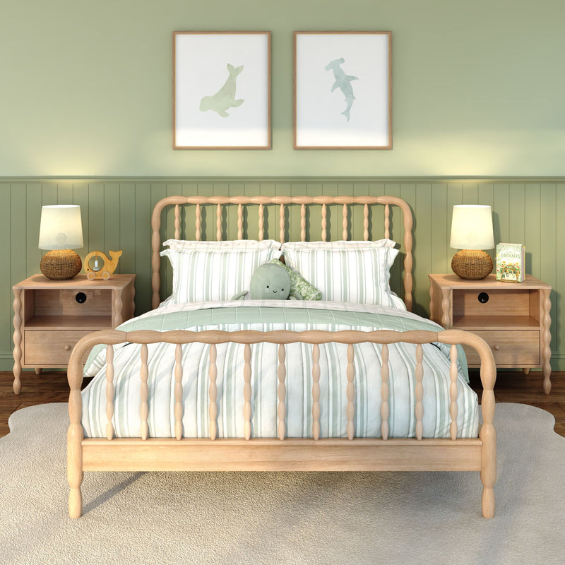 Children's bedroom with light wood spindle bed, striped green-and-white bedding, plush sea creature pillow, matching nightstands and lamps against sage green wainscoting with coastal framed prints