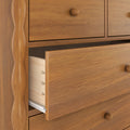 Close-up of a wooden dresser with a partially open drawer, visible wood grain, round wooden knob and interior joinery