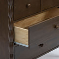 Dark brown wooden dresser with turned spindle detail and partially open drawer revealing light pine interior, metal drawer slide and round wooden knob on smooth stained finish