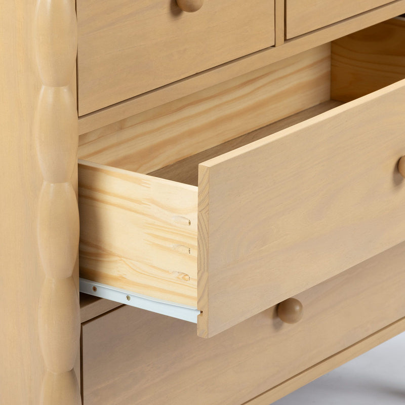 Light wood bedroom dresser with open drawer, close-up showing natural pine grain, wooden knob and metal drawer slide