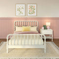 Pastel pink nursery with white spindle bed, yellow gingham bedding, floral framed wall art, scalloped wainscoting and bedside lamp