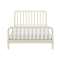 Ivory spindle bed frame with curved headboard and footboard and white tufted mattress on a plain white background