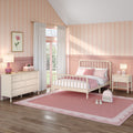 Pastel pink girl's bedroom with scalloped wainscoting, cream spindle bed, gingham pillows, white dresser, pink rug and sheer curtains