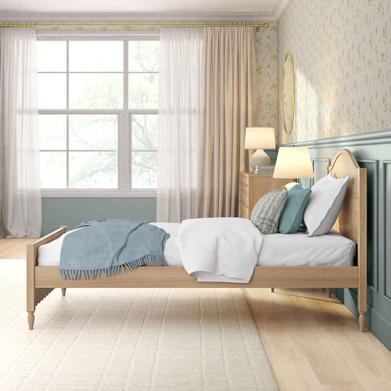 Bright airy bedroom interior with light wood bed, white bedding, blue throw blanket and decorative pillows, bedside lamps on a wooden dresser, large window with sheer curtains, floral wallpaper and soft wood flooring — cozy modern farmhouse bedroom decor