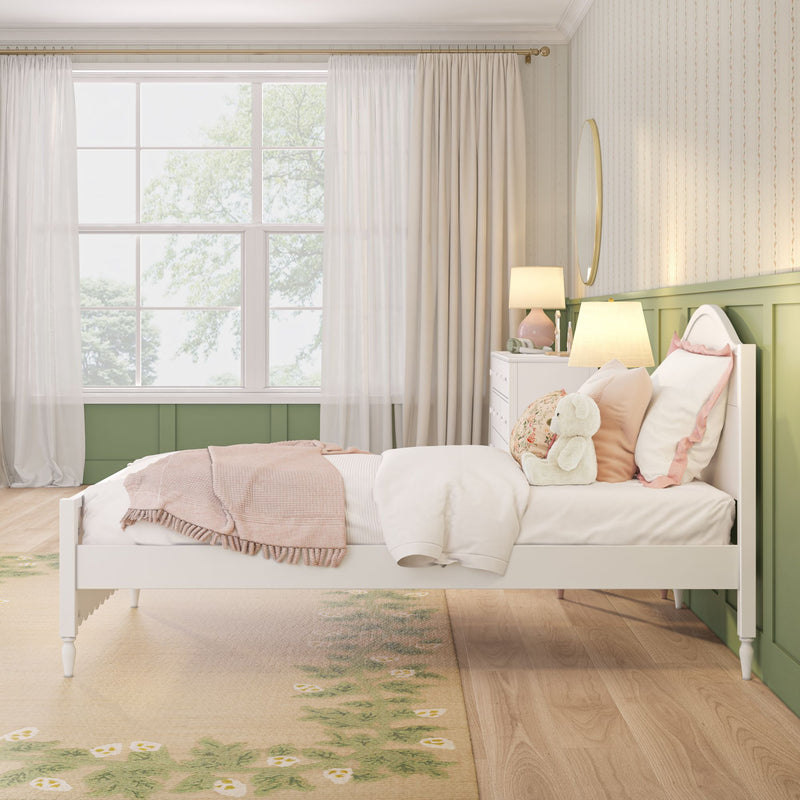 Pastel girls bedroom with white bed frame, pink bedding, plush teddy bear, bedside lamps, green wainscoting and sheer curtains