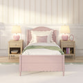 Pastel pink bed with scalloped headboard, floral striped wallpaper, wooden nightstands and pink lamps in a cozy kids' bedroom