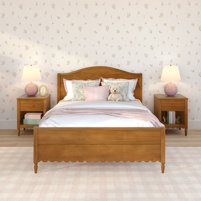 Cozy girls bedroom with wooden bed, pink bedding and throw, teddy bear on pillows, floral wallpaper, wooden nightstands and pink table lamps