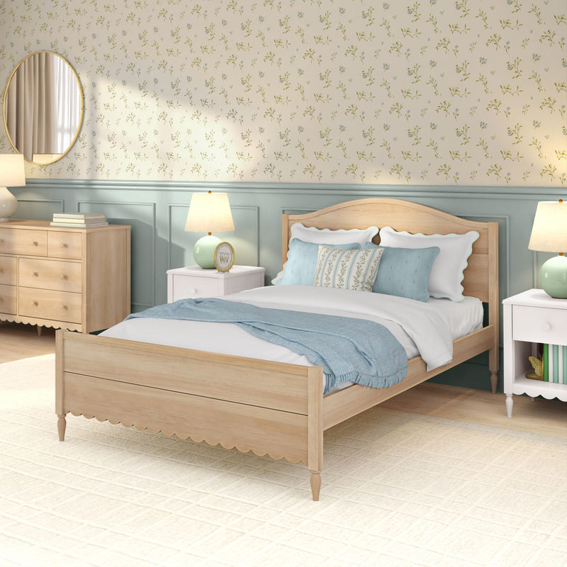 Cozy cottage-style bedroom with light wood bed frame, white linens, blue throw and decorative pillows, floral wallpaper, matching nightstands with lamps and wooden dresser