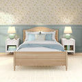 Coastal cottage bedroom interior with light wood bed, scalloped headboard, blue-and-white bedding, pastel floral wallpaper, white nightstands and mint table lamps