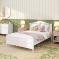 Cozy pastel kids bedroom with white wooden twin bed, pink bedding and throw, floral accent pillows and teddy bear, green wainscoting, floral area rug, matching pink nightstands with lamps, and white dresser with round mirror.