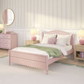 Pastel pink girls' bedroom with scalloped pink bed frame, white bedding and green throw, floral striped wallpaper, round gold mirror, pink lamps and dresser