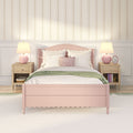 Pastel pink scalloped bed with white bedding and blush velvet pillows in a cozy girls' bedroom with vintage floral striped wallpaper, wooden nightstands and pink table lamps