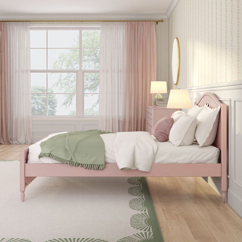 Pink twin bed in a girls' pastel bedroom with green throw blanket, blush curtains, large window, round mirror and bedside lamps — modern kids' room decor